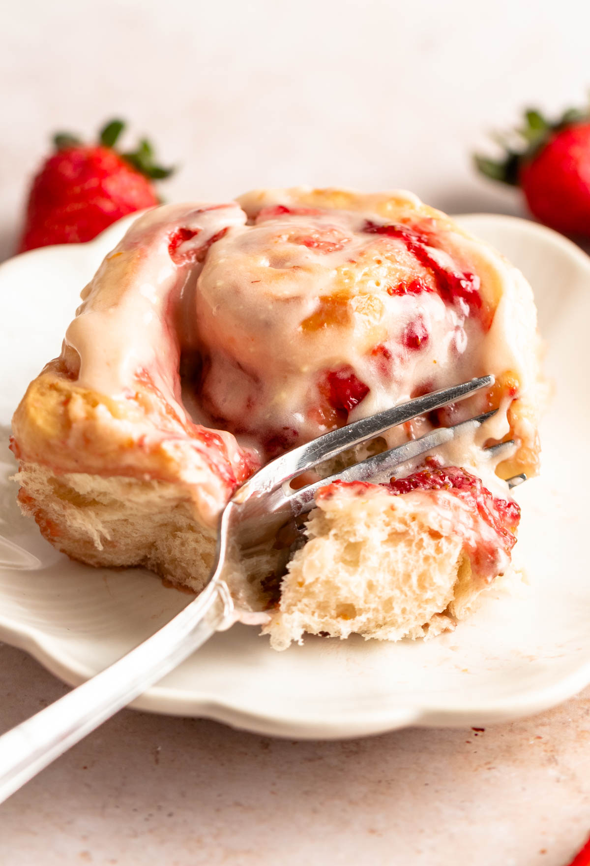 Strawberry cinnamon roll on a plate with a fork.