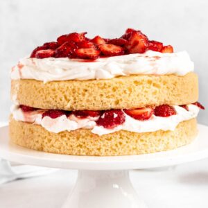 Strawberry shortcake birthday cake on a white cake platter.