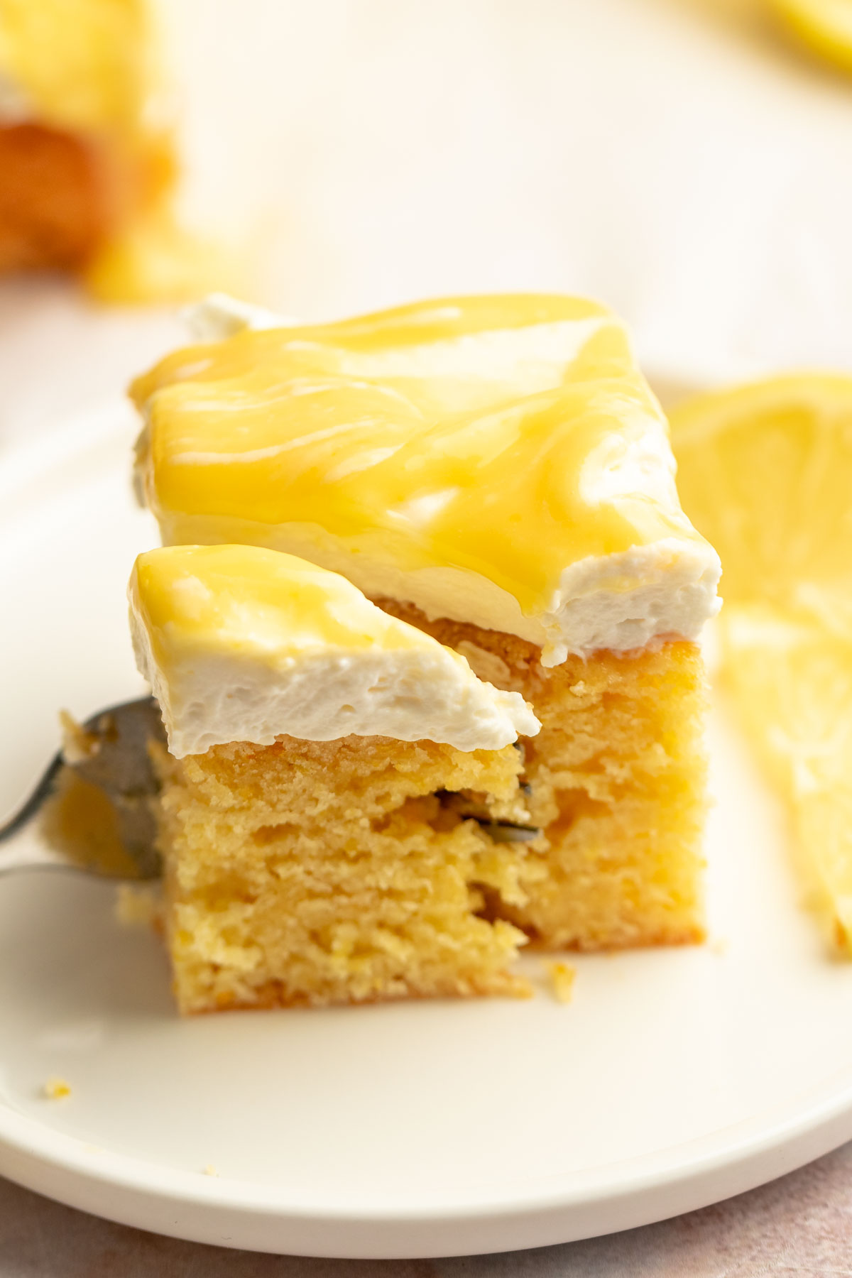 Slice of limoncello mascarpone cake on a plate with a fork inserted into the slice.