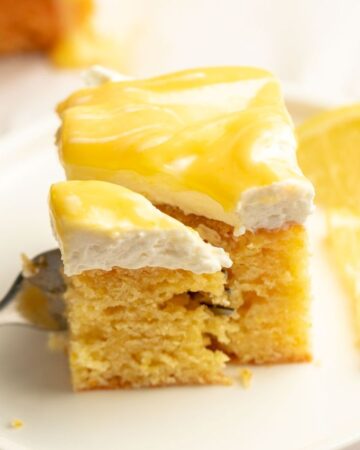 Slice of limoncello mascarpone cake on a plate with a fork inserted into the slice.