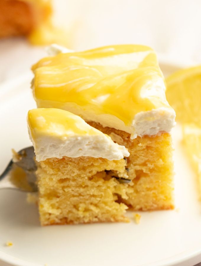 Slice of limoncello mascarpone cake on a plate with a fork inserted into the slice.