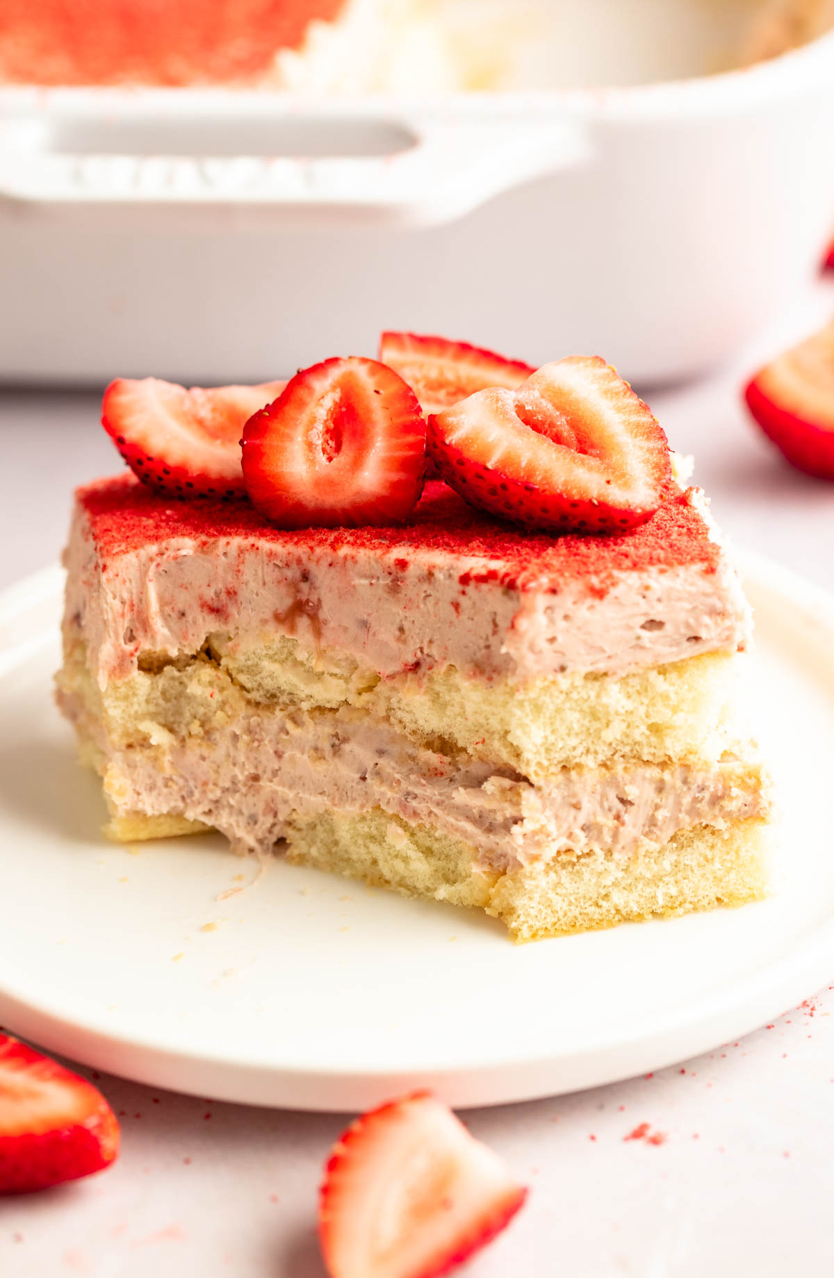 Slice of strawberry tiramisu with a bite missing.