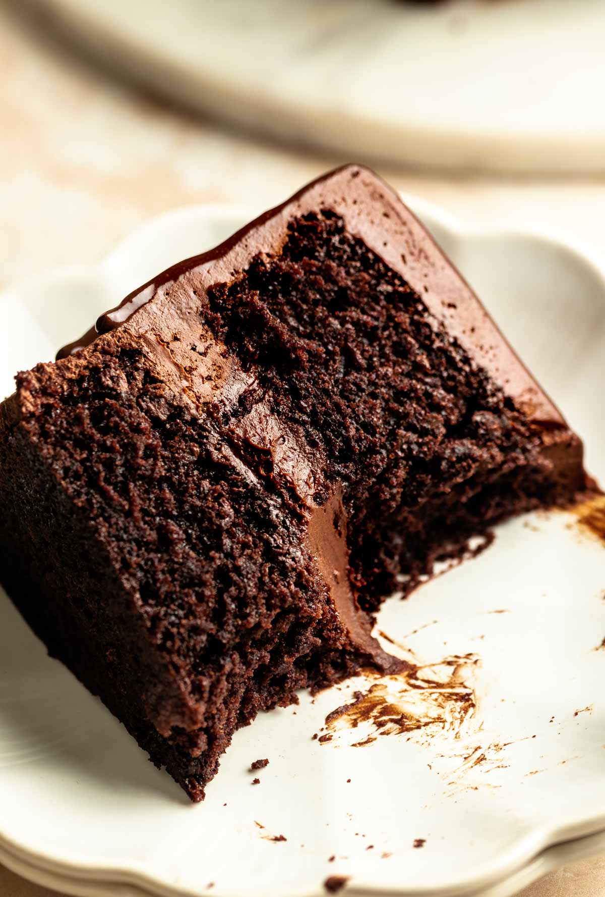 Slice of chocolate ganache cake on a plate with a bite missing.