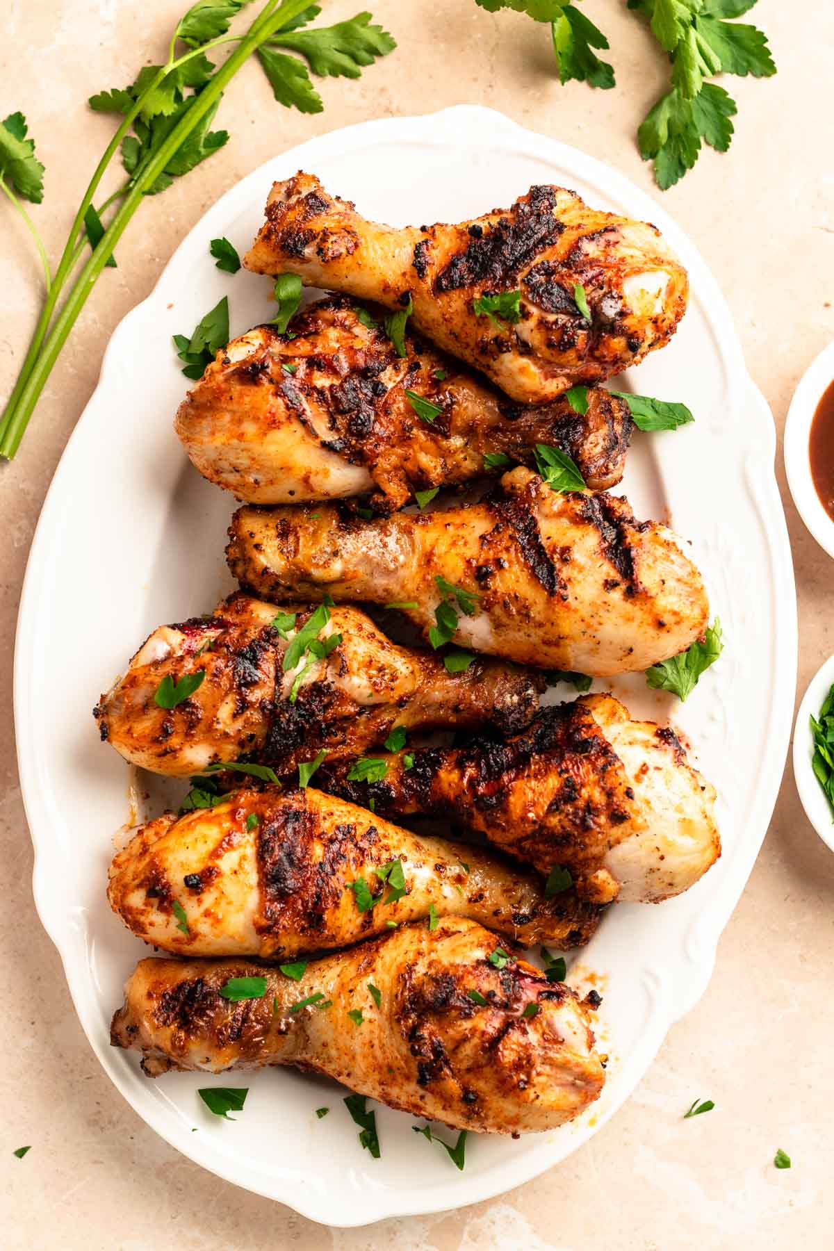 Top of a large plate with grilled chicken drumsticks.