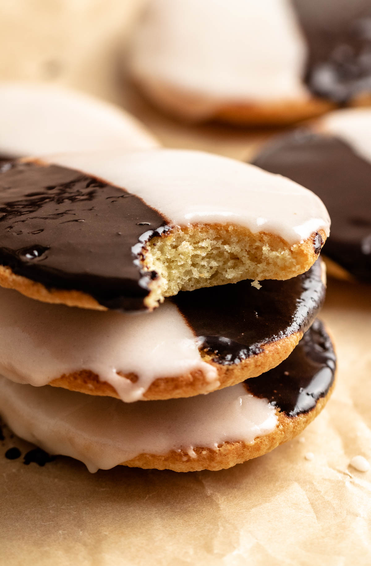 A stack of black and white cookies with the top one missing a bite.