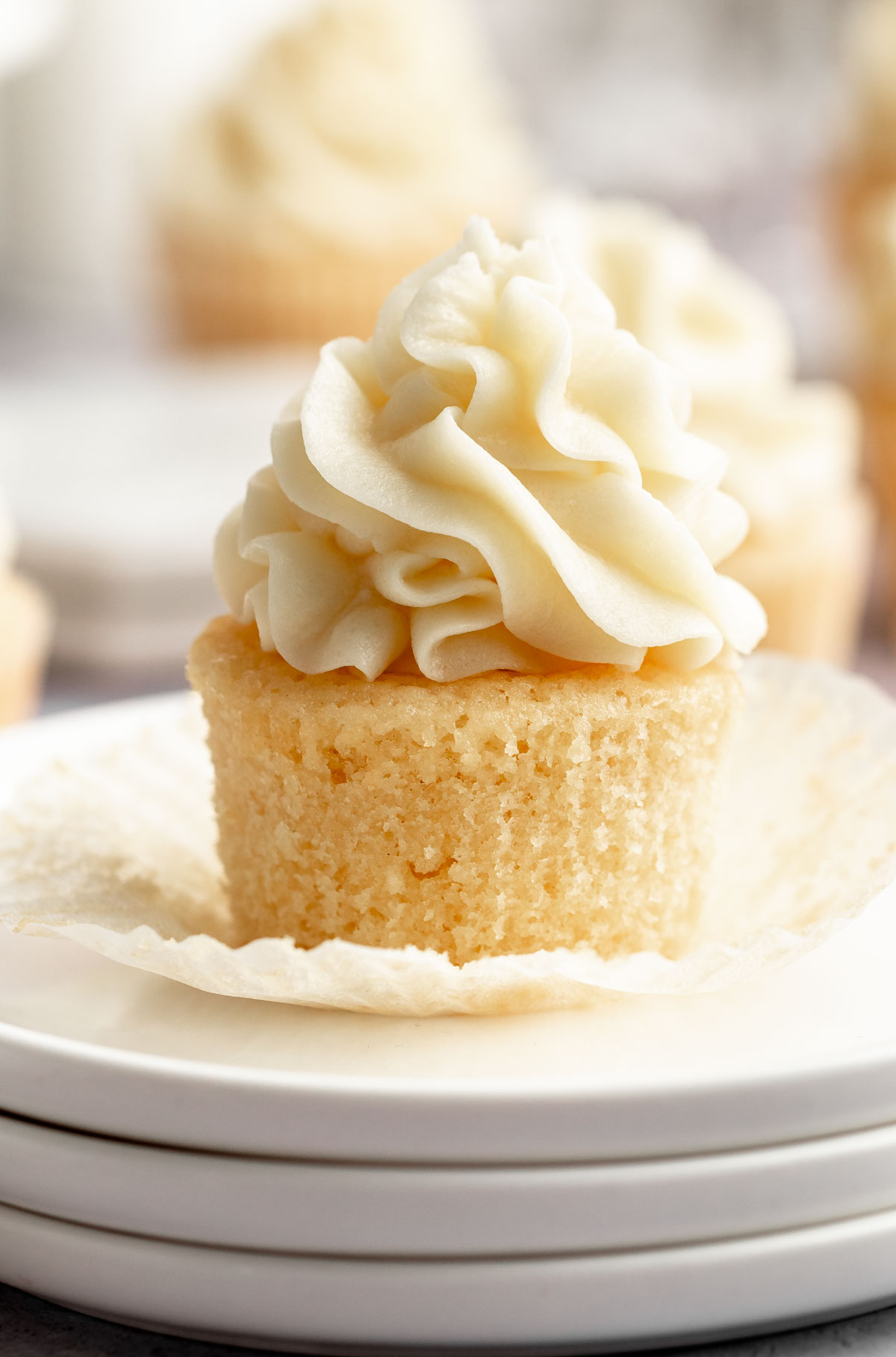 Vanilla cupcake on a stack of white plates.