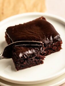 Slice of buttermilk chocolate cake on a white plate with a fork.