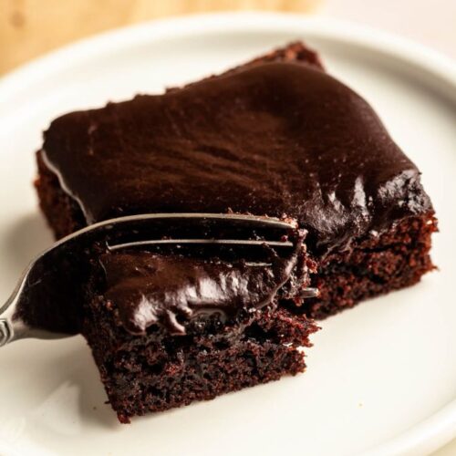 Slice of buttermilk chocolate cake on a white plate with a fork.