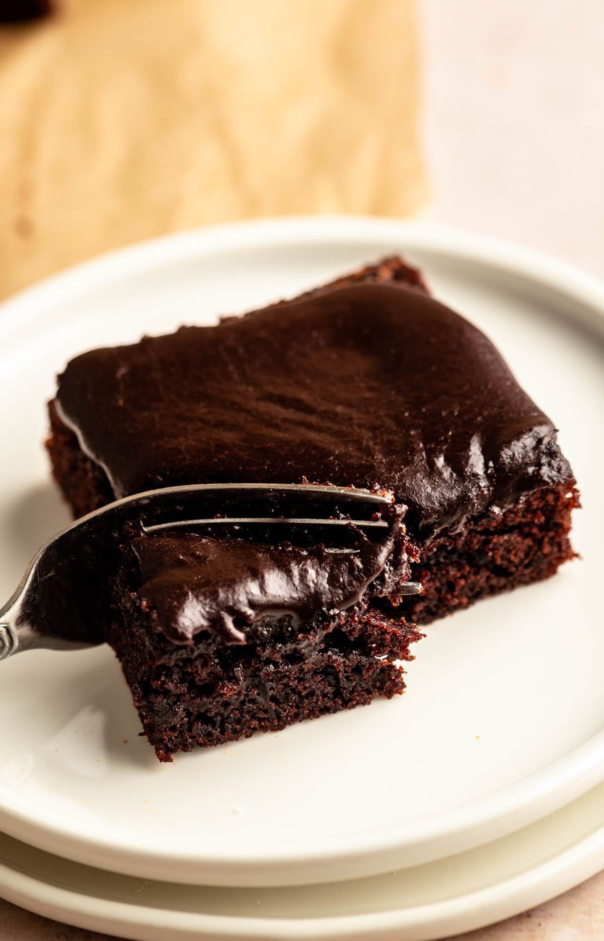 Slice of buttermilk chocolate cake on a white plate with a fork.