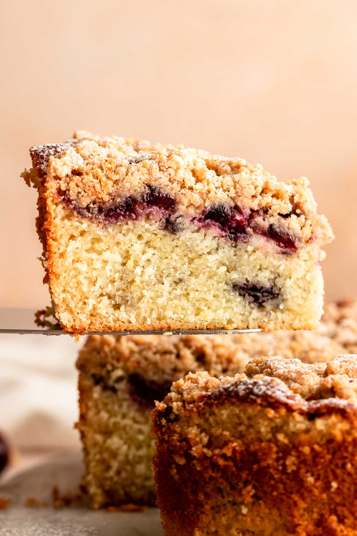 Slice of cherry crumble cake pulled away from the cake.