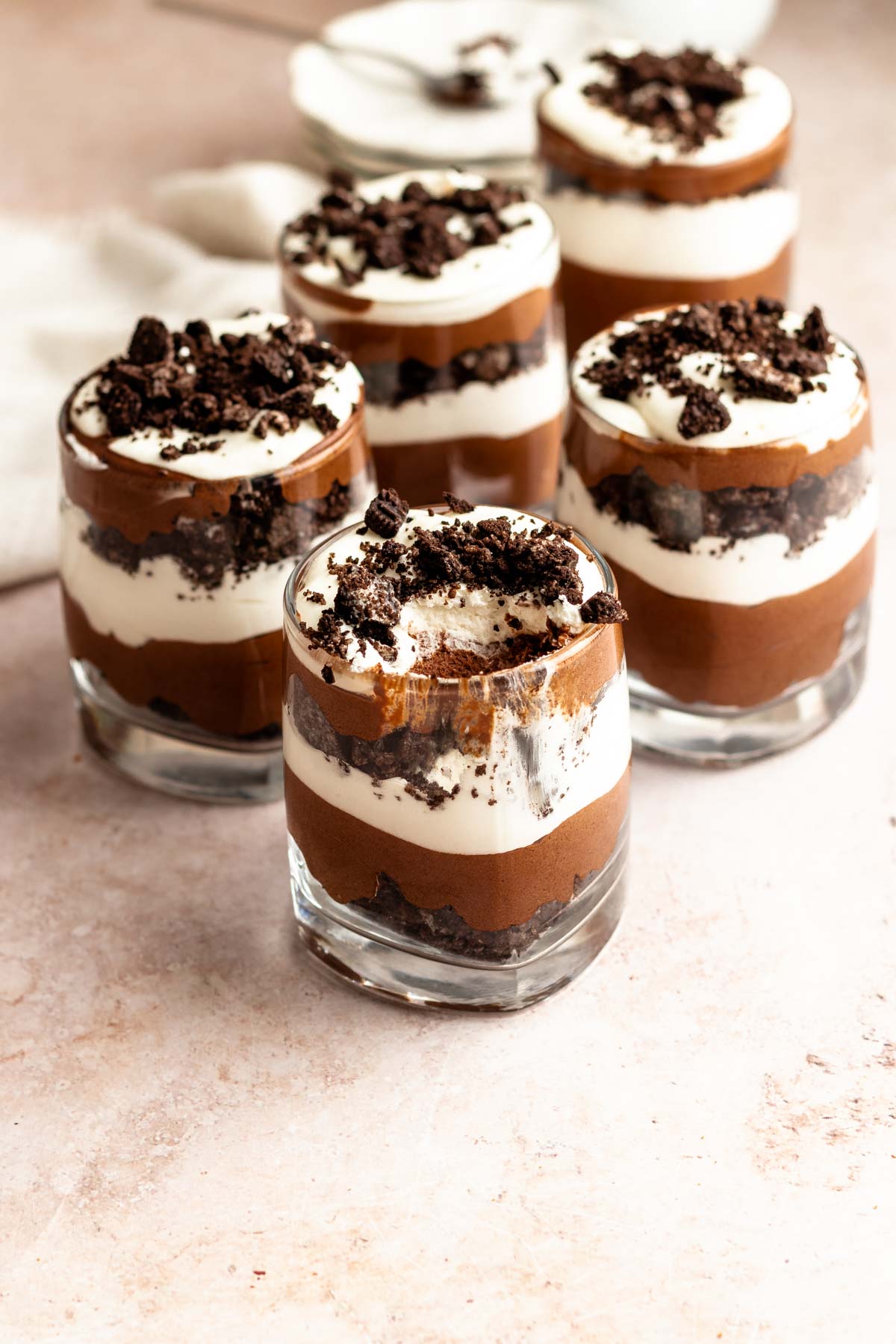 Chocolate parfait mousse cups with the middle one missing a bite.