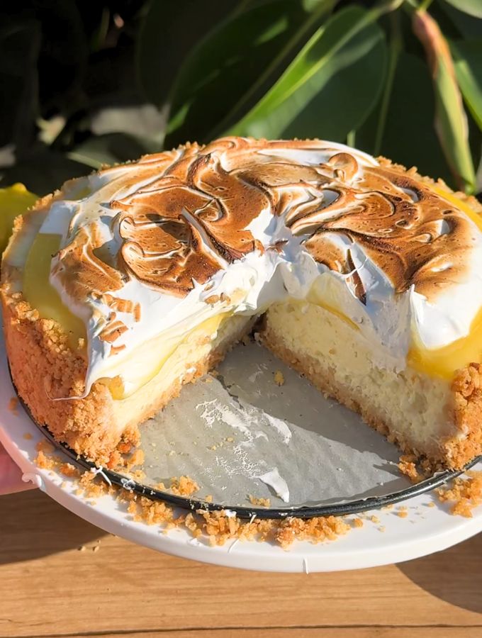 Slice missing from a lemon meringue cheesecake.