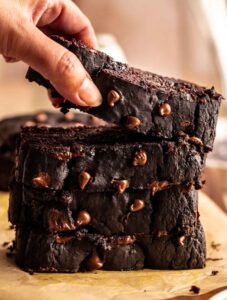 Stack of chocolate pumpkin bread slices with the top one lifted.
