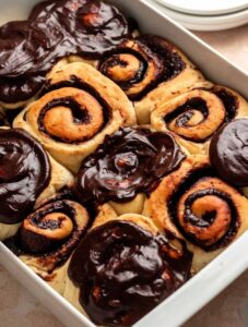 Chocolate cinnamon rolls with chocolate icing on top.