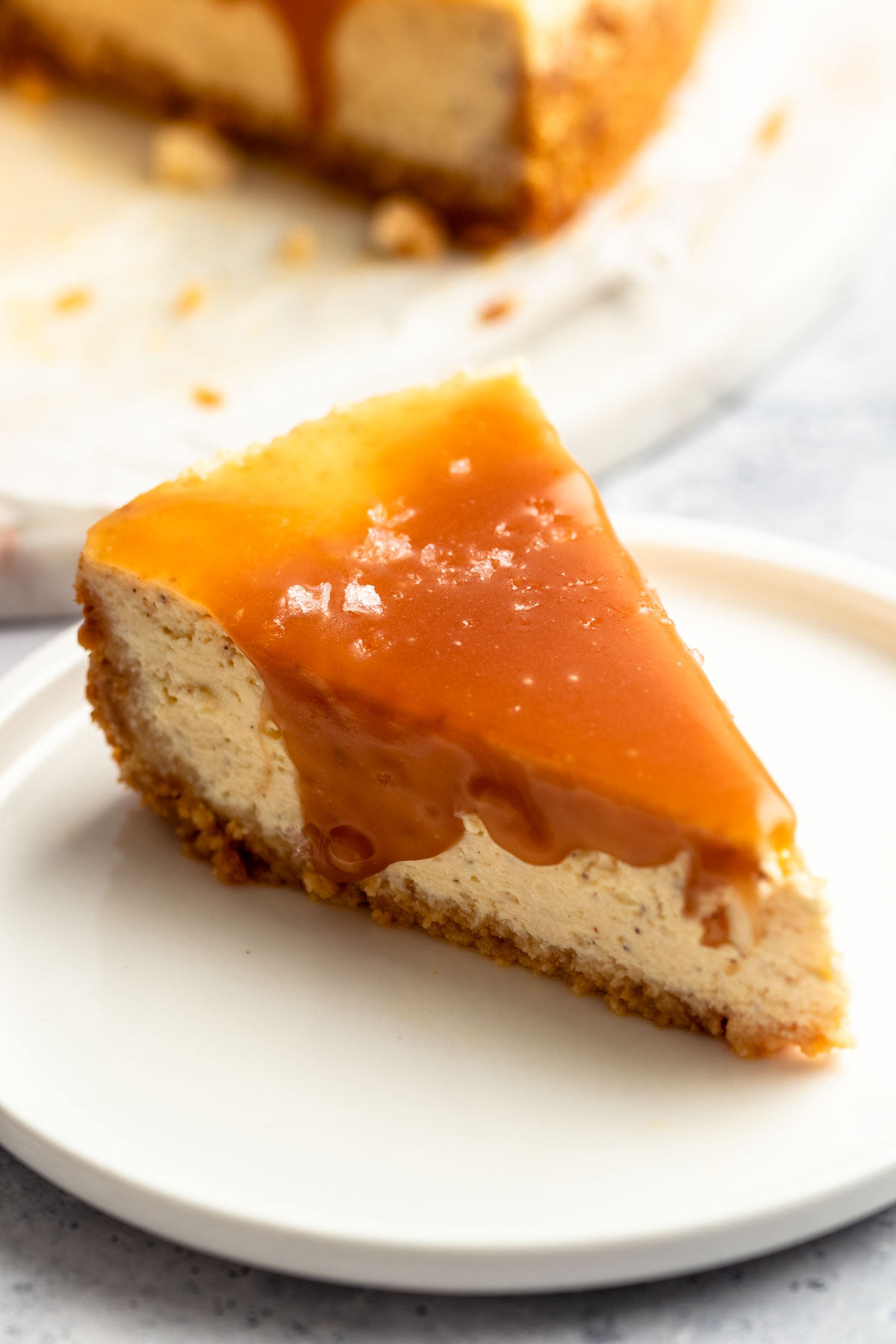 Slice of salted caramel cheesecake with caramel sauce on top.