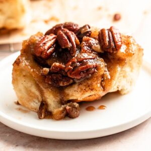 Slice of pecan sticky buns on a white plate.