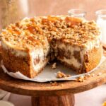 Apple crumble cheesecake sliced open on a wooden cake stand.