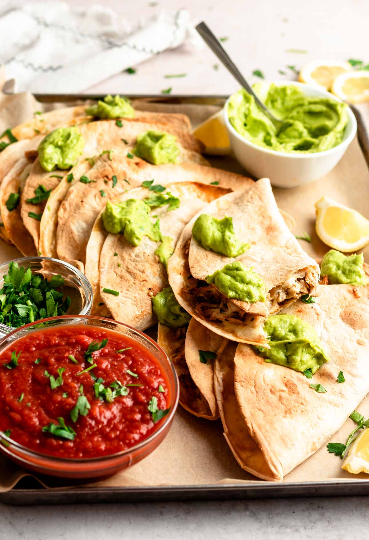 Pile of baked chicken tacos with avocado sauce on top.