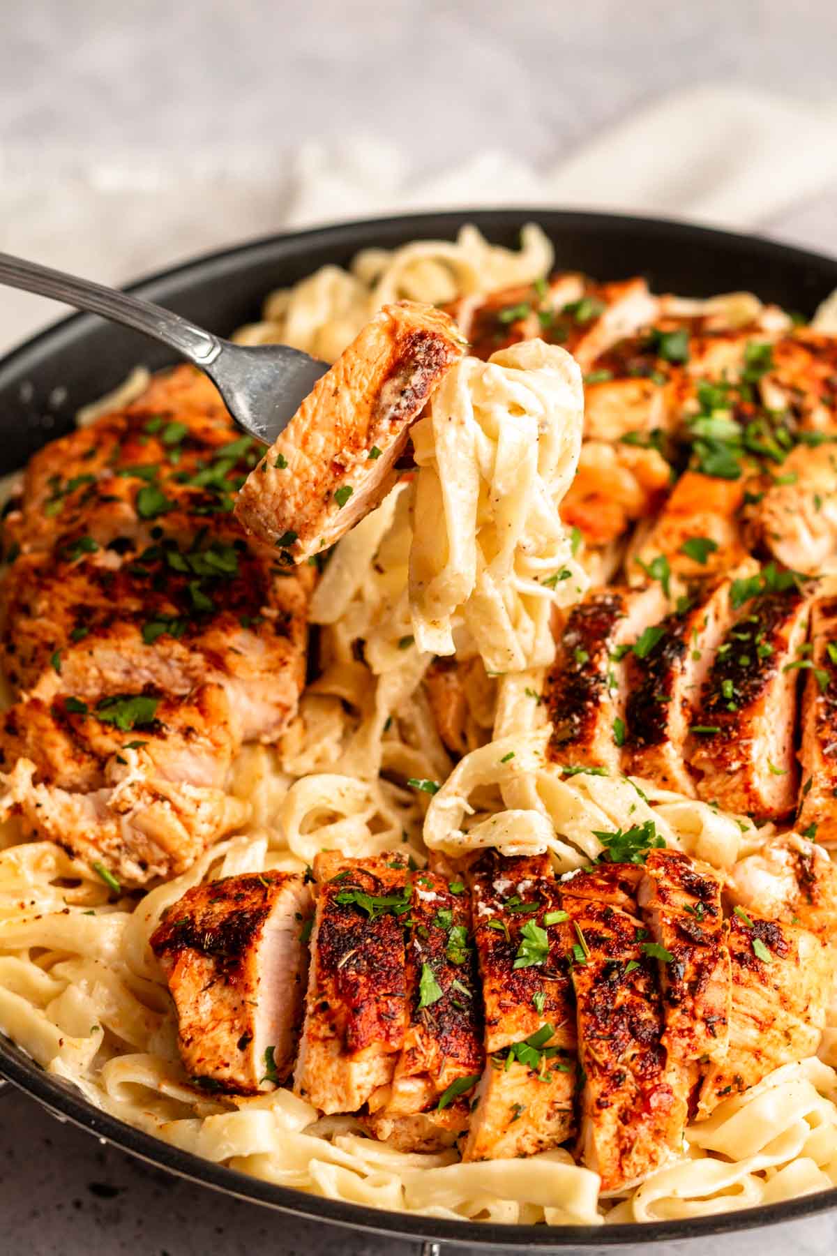 Fork with blackened chicken and fettuccine alfredo.