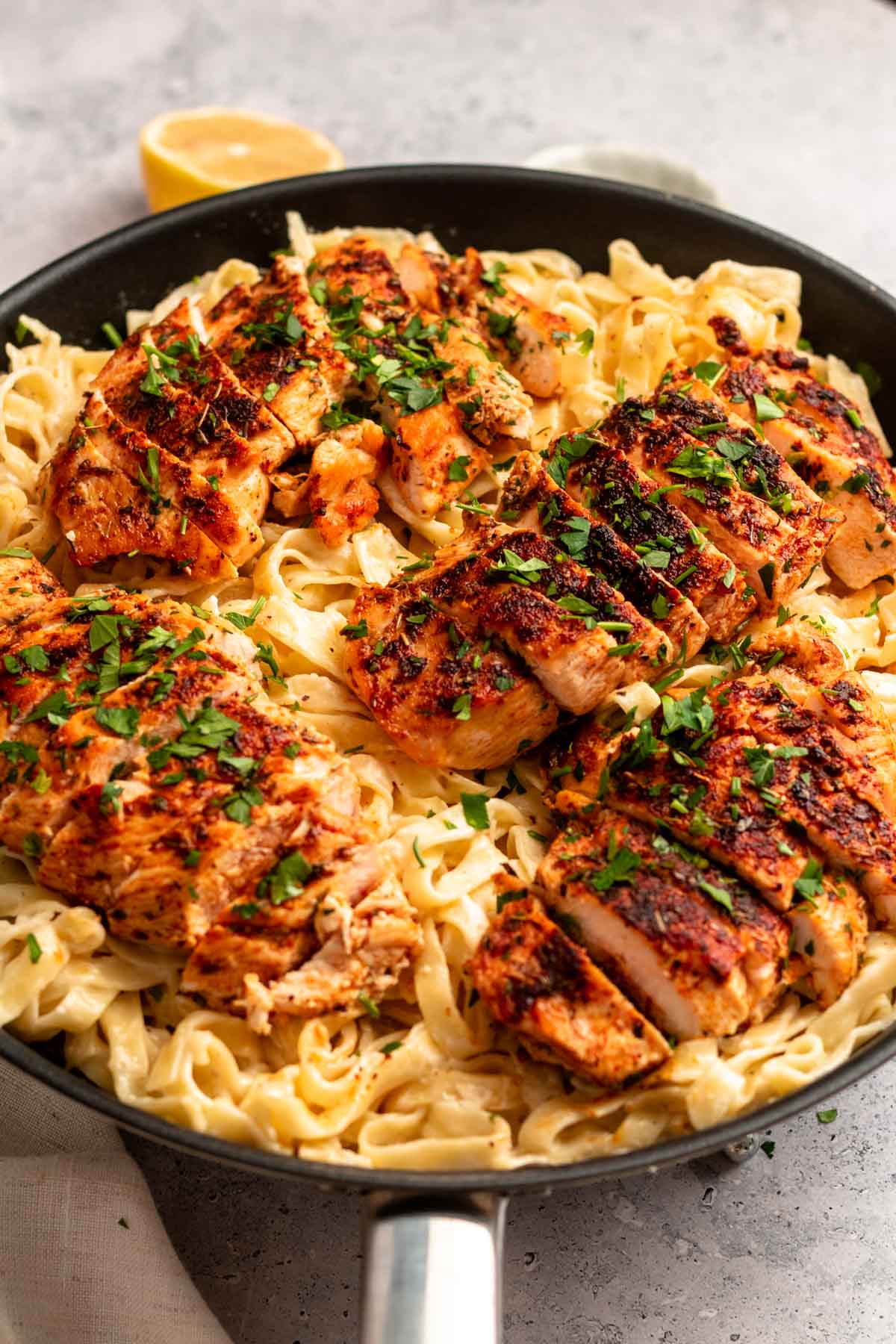 Close up shot of blackened chicken alfredo in a pan.