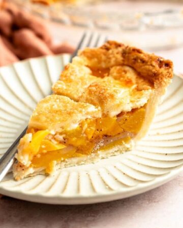 Slice of peach pie with canned peaches.