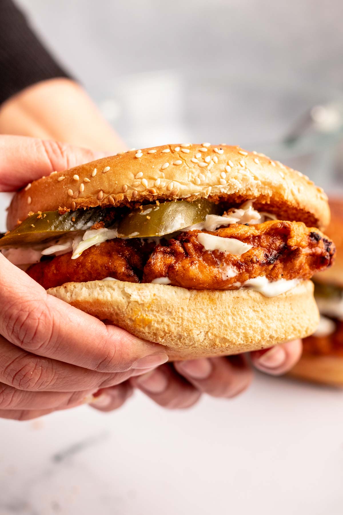 Hands holding a hot chicken sandwich.