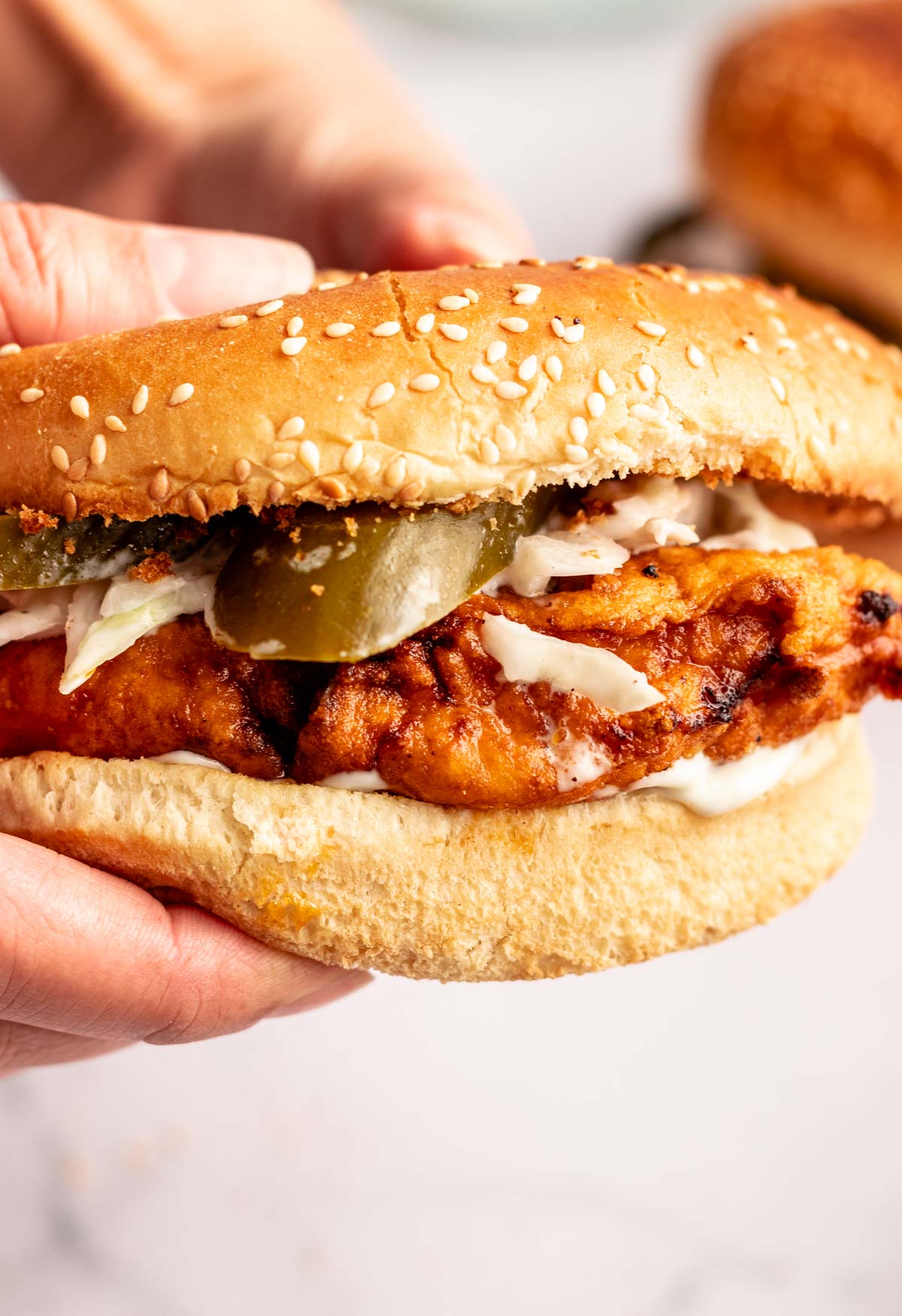 Hands holding a Nashville hot chicken sandwich.