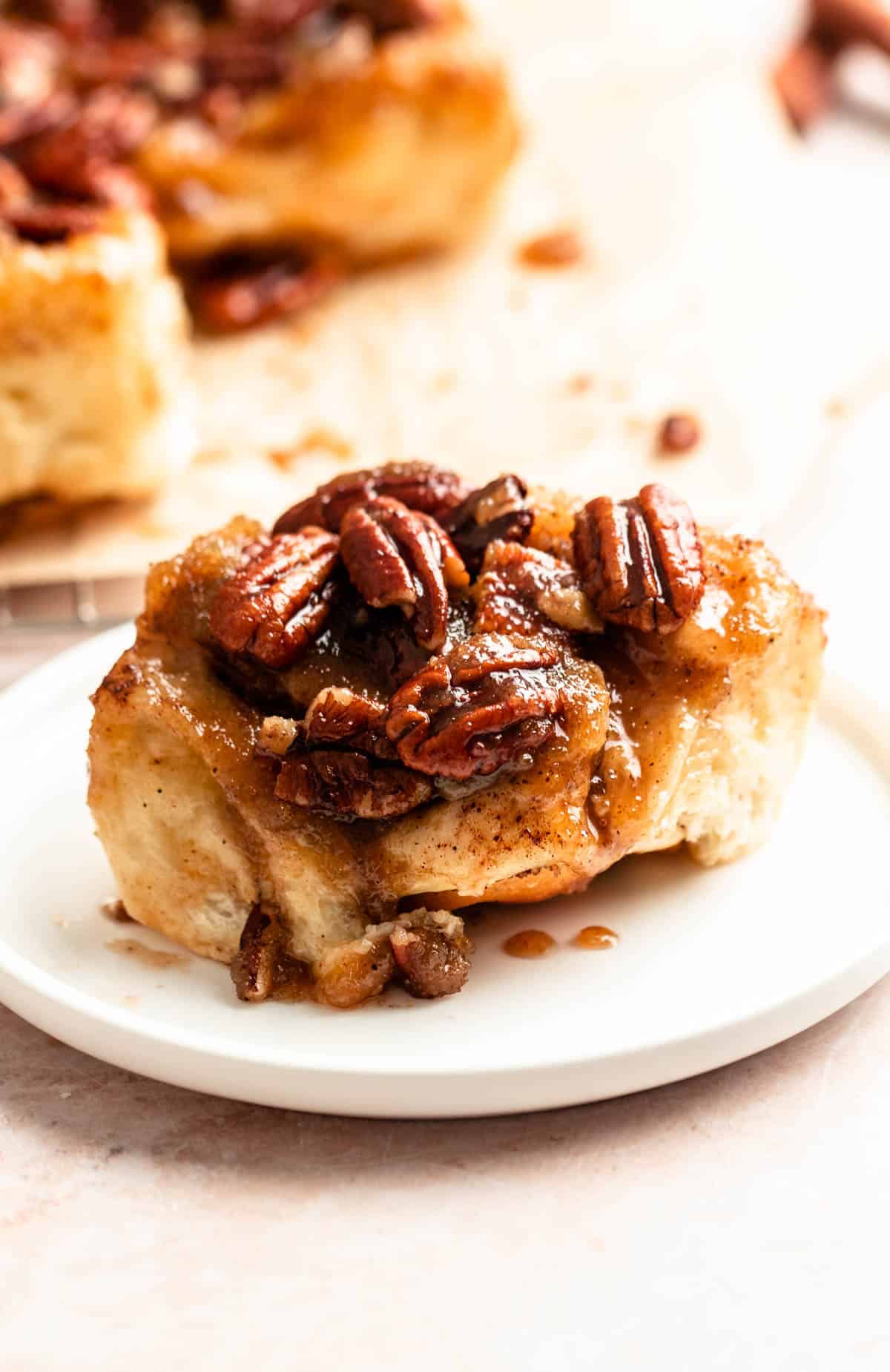 Slice of pecan sticky bun on a white plate.