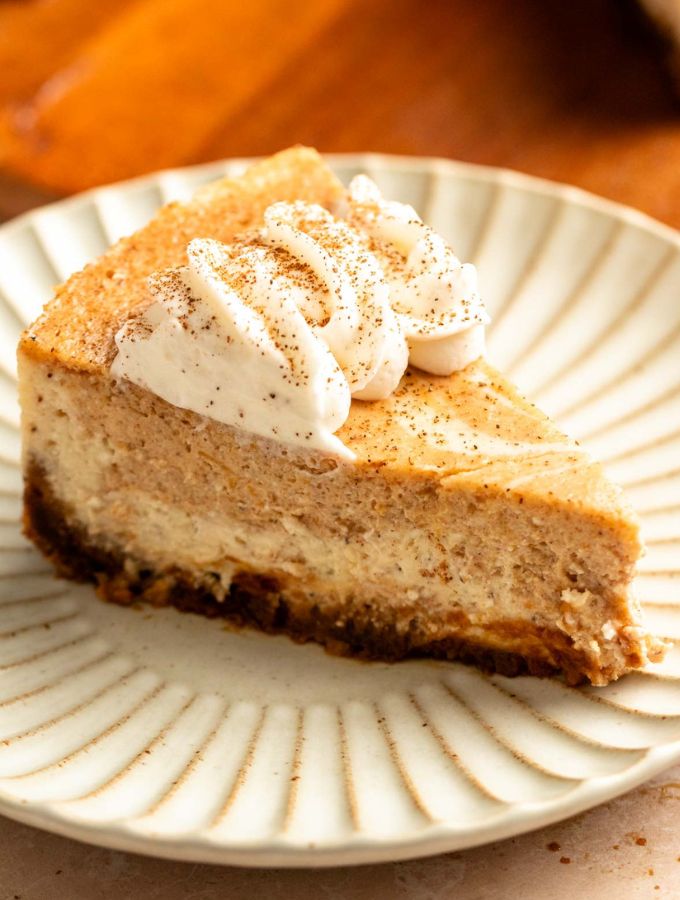 Slice of pumpkin swirl cheesecake on a white plate.