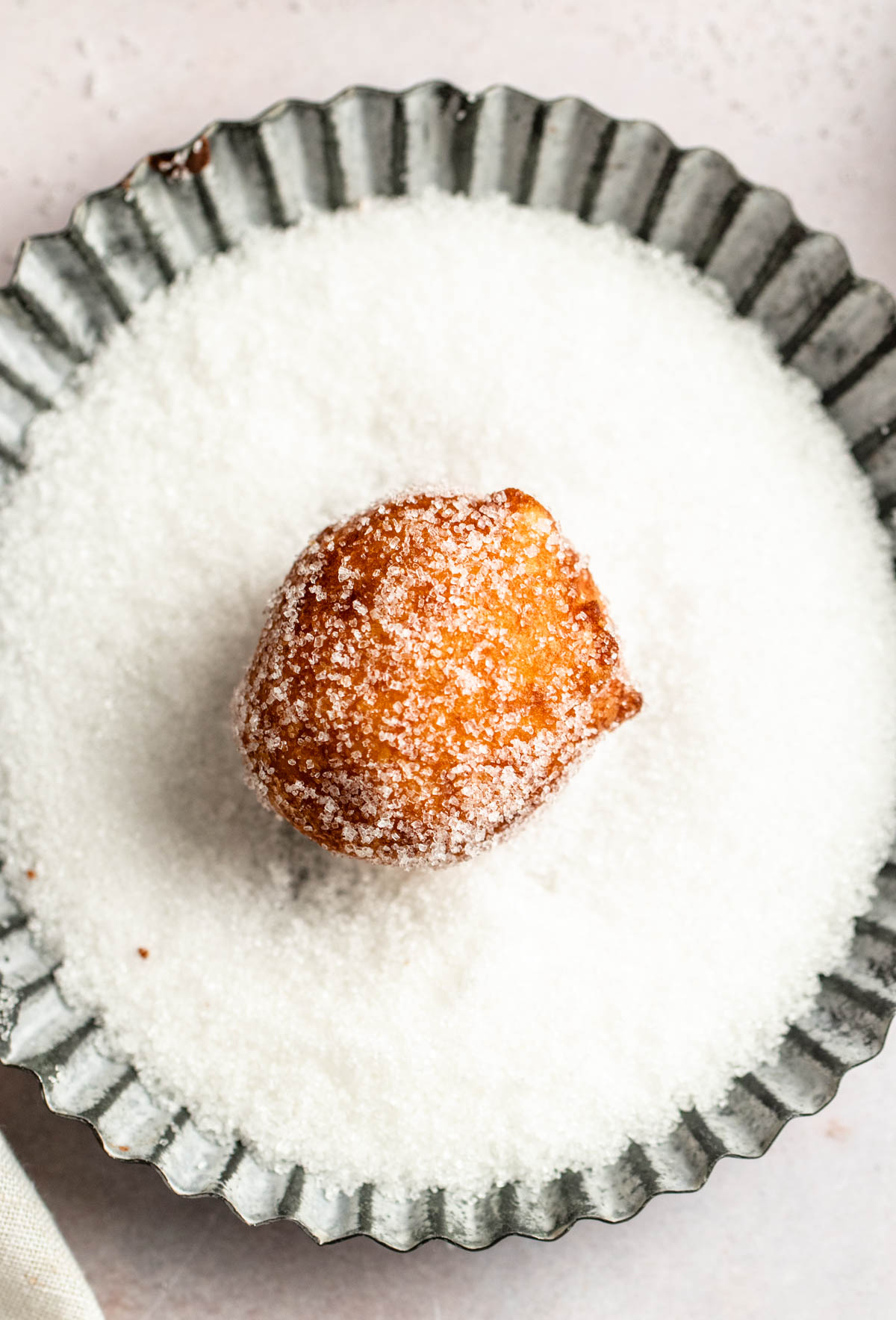 Donut hole in a bowl with sugar.