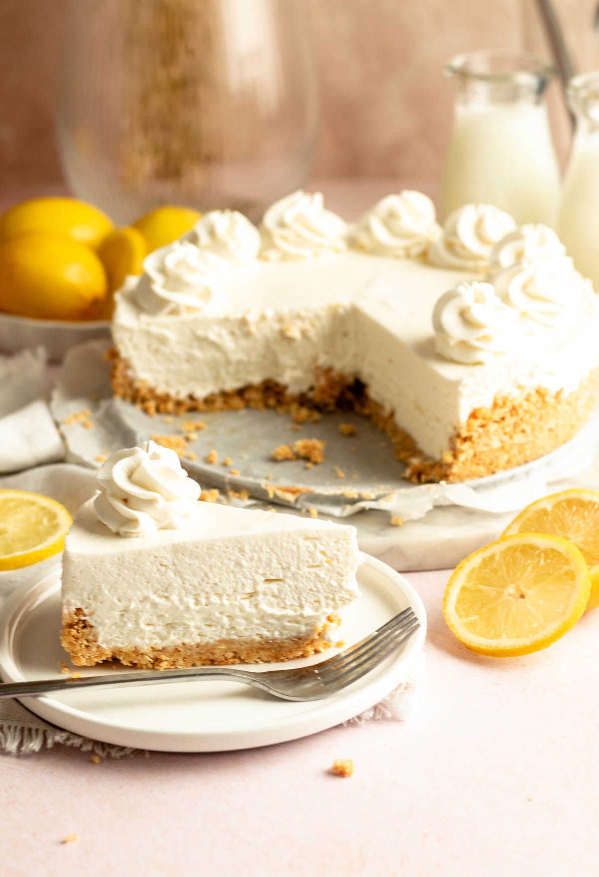 Slice of no bake cheesecake with cool whip next to the whole cheesecake.