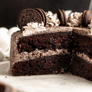 Chocolate Oreo cake sliced open on a white cake plate.