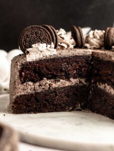 Chocolate Oreo cake sliced open on a white cake plate.