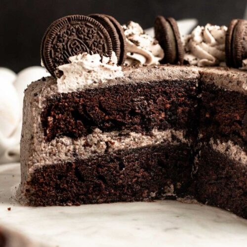 Chocolate Oreo cake sliced open on a white cake plate.