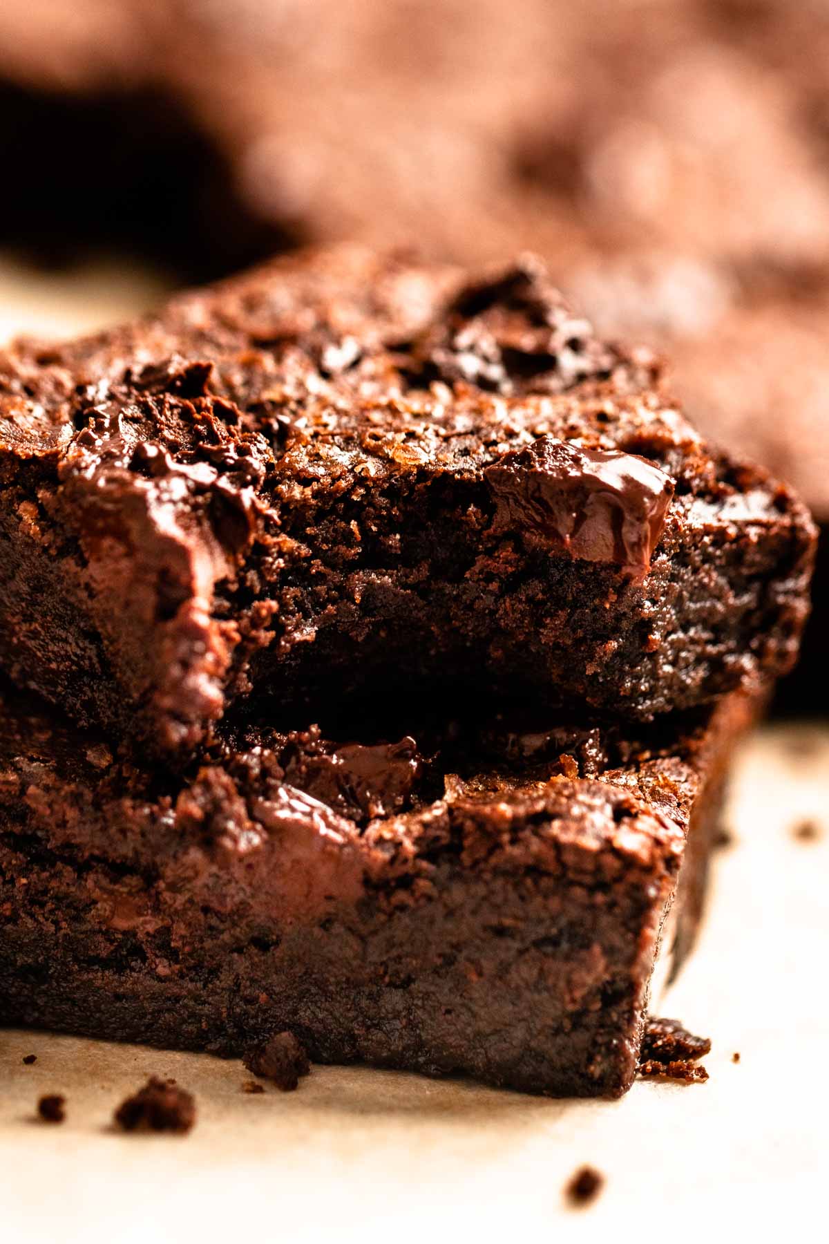 Stack of two dark chocolate brownies with the top one missing a bite.