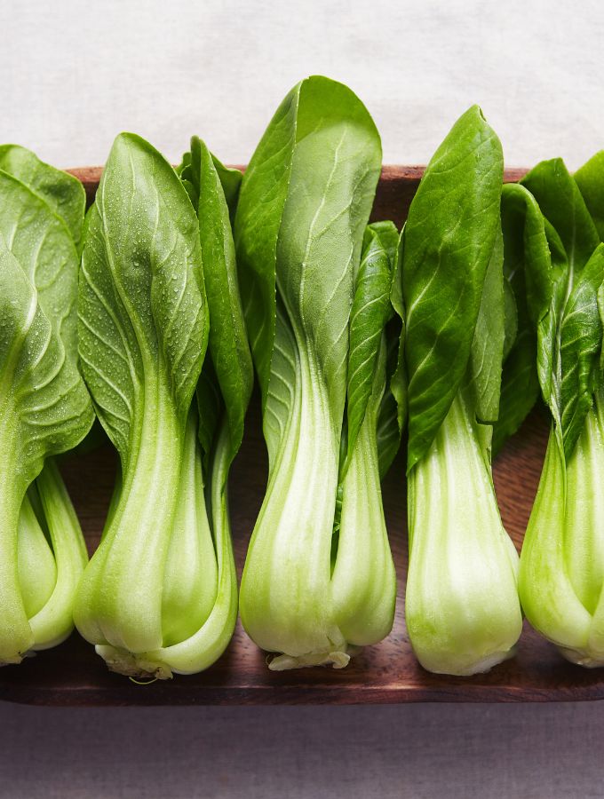 5 bok choy on a wooden board.