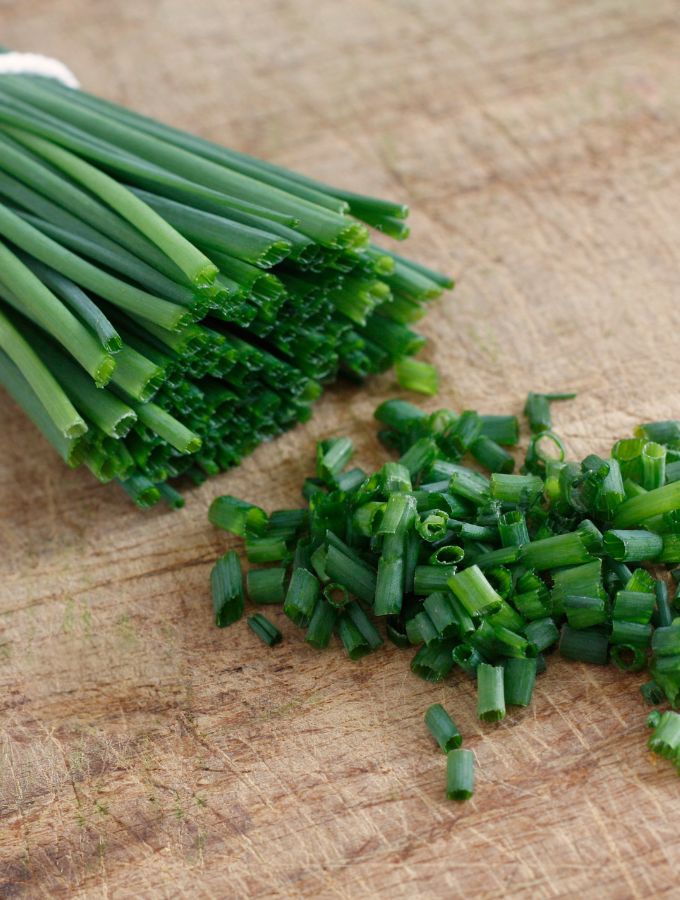 Chopped chives on a wooden board.