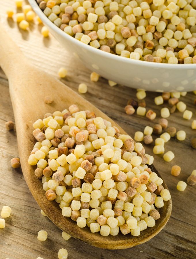 Wooden spoon holding Fregola pasta.