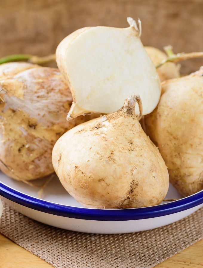 Jicama on a plate with the top one cut in half.