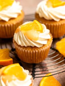 Orange cupcakes on a round cooling rack.