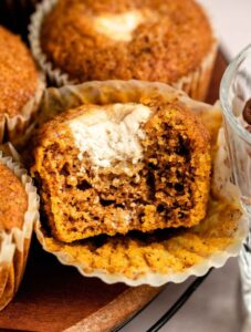 Close up shot of pumpkin cream cheese muffins with the middle one cut in half.