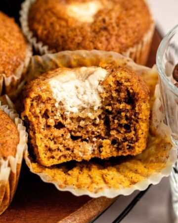 Close up shot of pumpkin cream cheese muffins with the middle one cut in half.