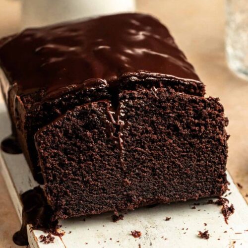 Sliced chocolate pound cake on a white wooden board.