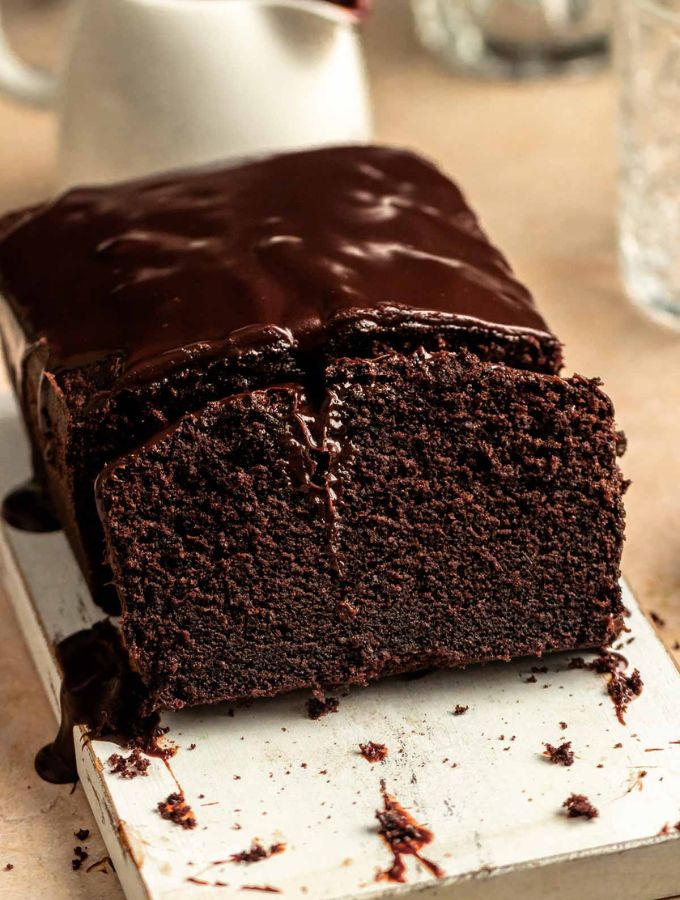 Sliced chocolate pound cake on a white wooden board.