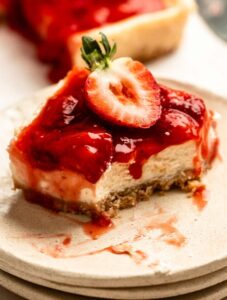 Bite missing from a slice of strawberry cheesecake bars.