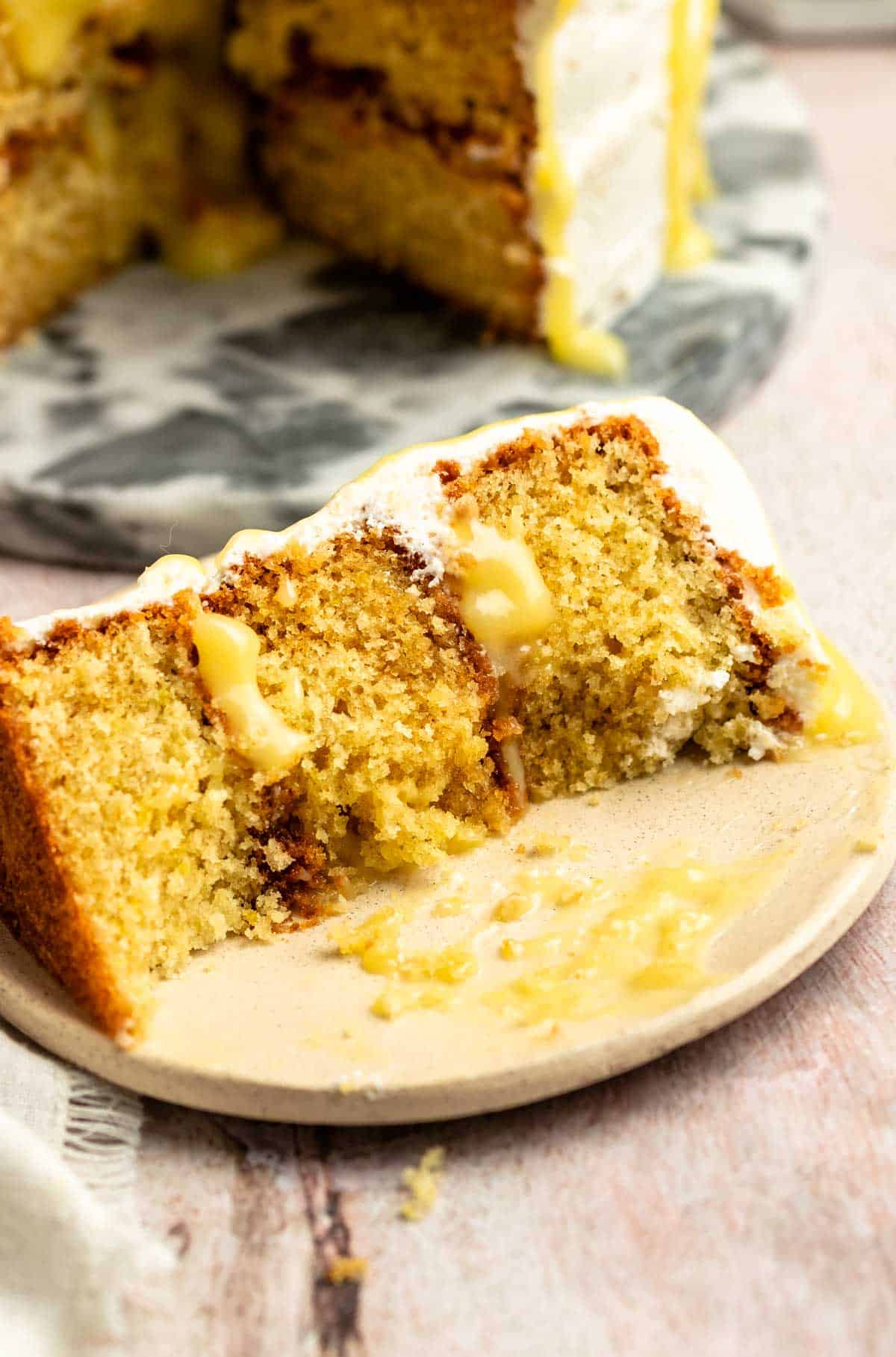 Slice of lemon curd cake with a bite missing from it.