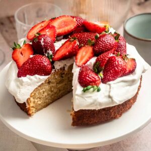 Slice missing from a strawberry whipped cream cake.