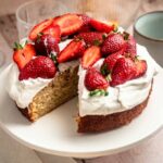 Slice missing from a strawberry whipped cream cake.