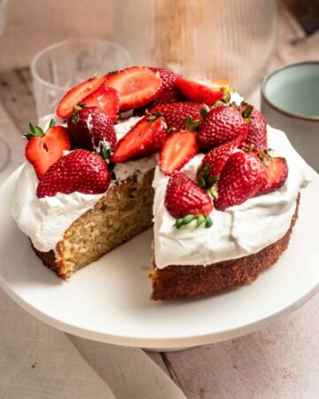 Slice missing from a strawberry whipped cream cake.