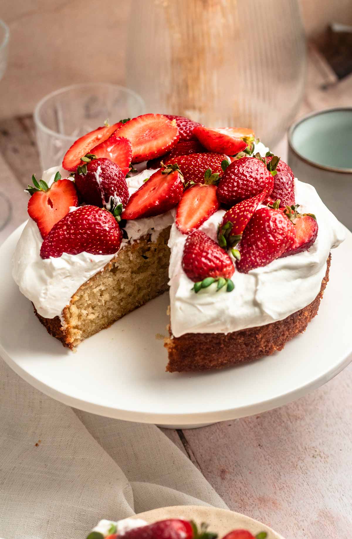 Slice missing from a strawberry whipped cream cake.